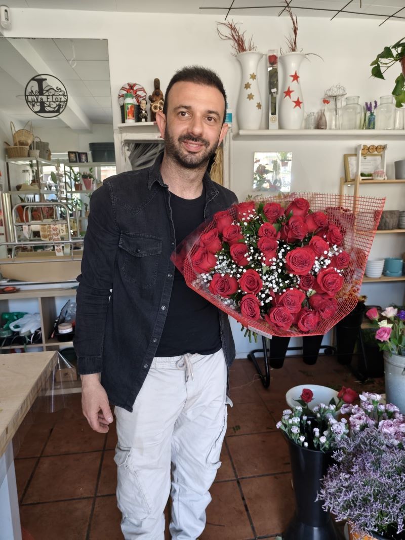 Lorenzo, florista de LuVaflors, con un ramo de rosas en la tienda de la Barceloneta